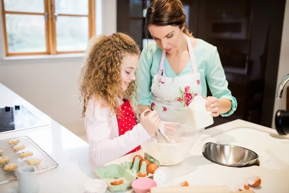 A mother and daughter baking a pizza cake together in the kitchen.
