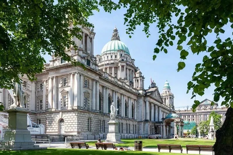 Belfast Town Hall on a sunny day with trees in the foreground.