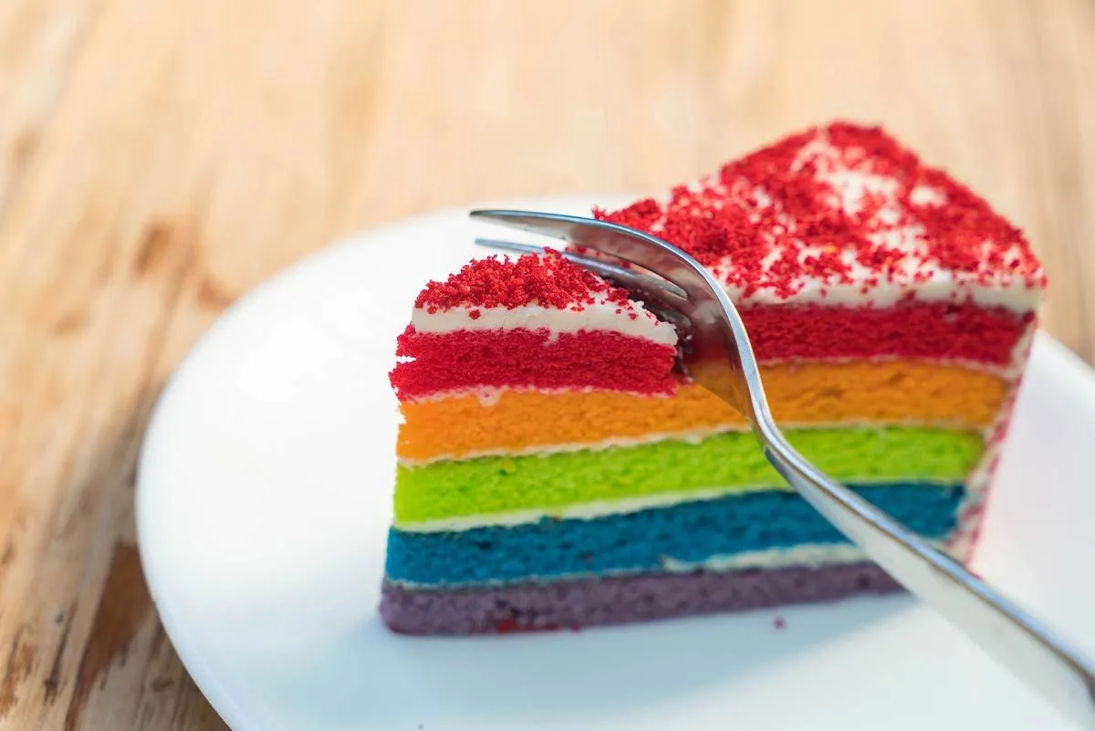 Fork slicing through a piece of rainbow Power Ranger cake.
