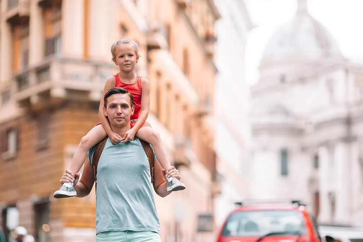 Dad walking through a city with his daughter on his shoulders.