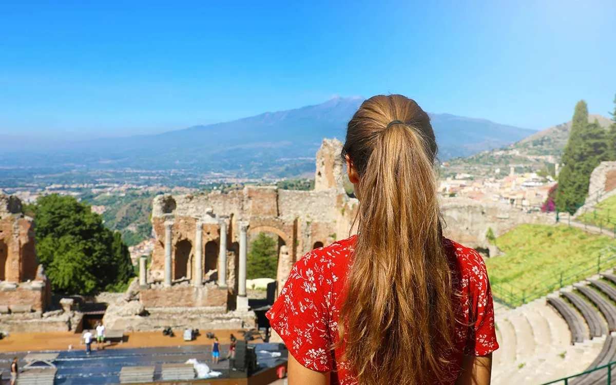 Young girl standing looking out over the view of ancient ruins in Greece.