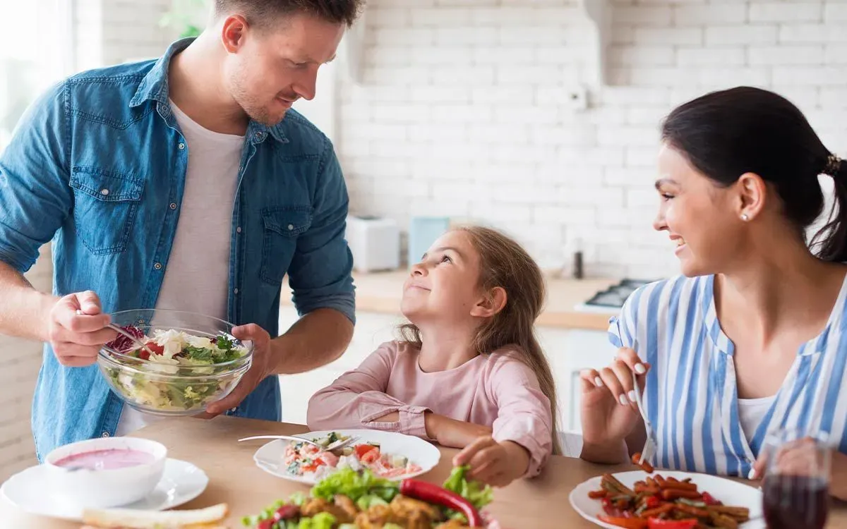 A family are sat at the table together sharing a meal, the salad they are eating will travel through the digestive system.