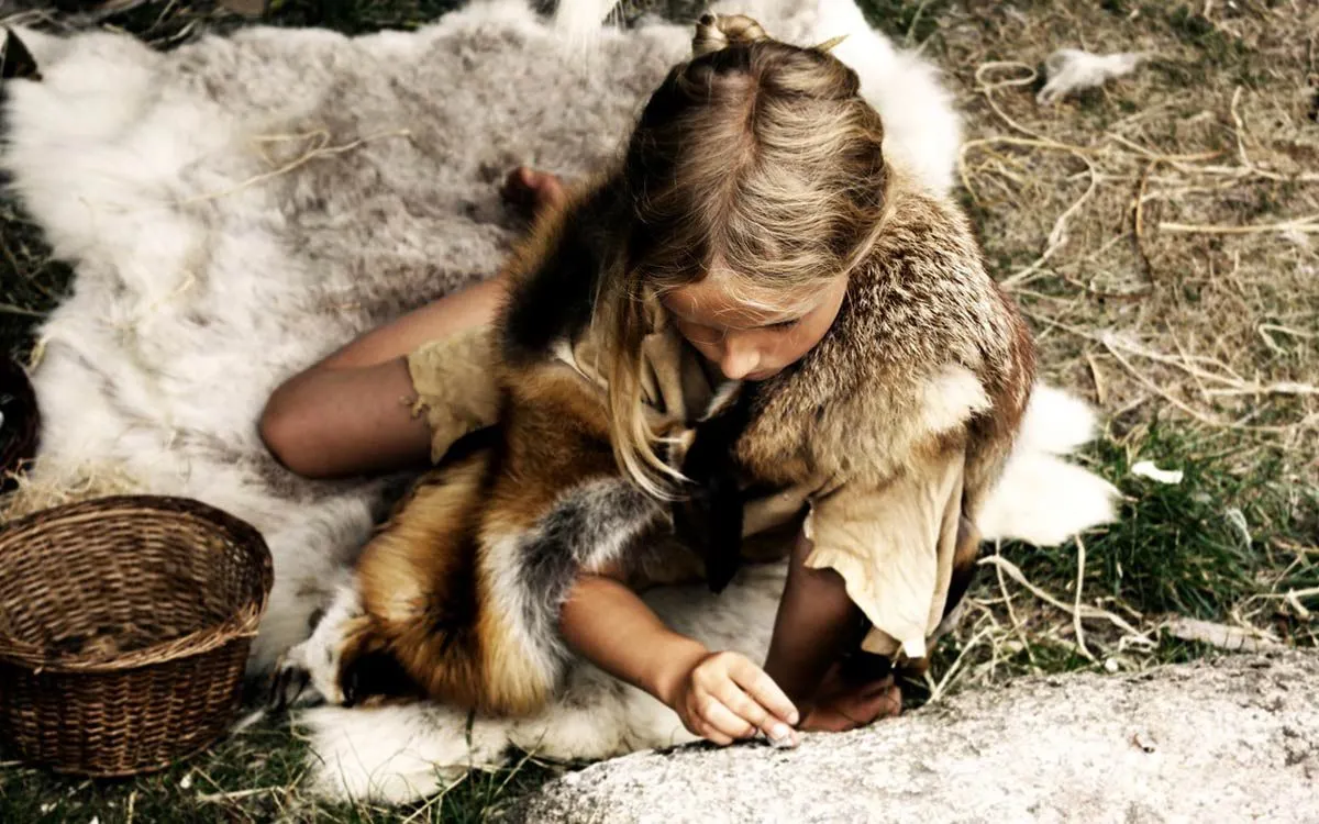 Little girl wearing fake animal furs like a Stone Age person.