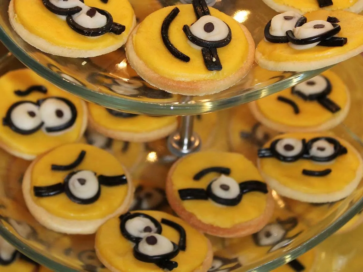 Lots of round, yellow minion cookies displayed on a cake stand.