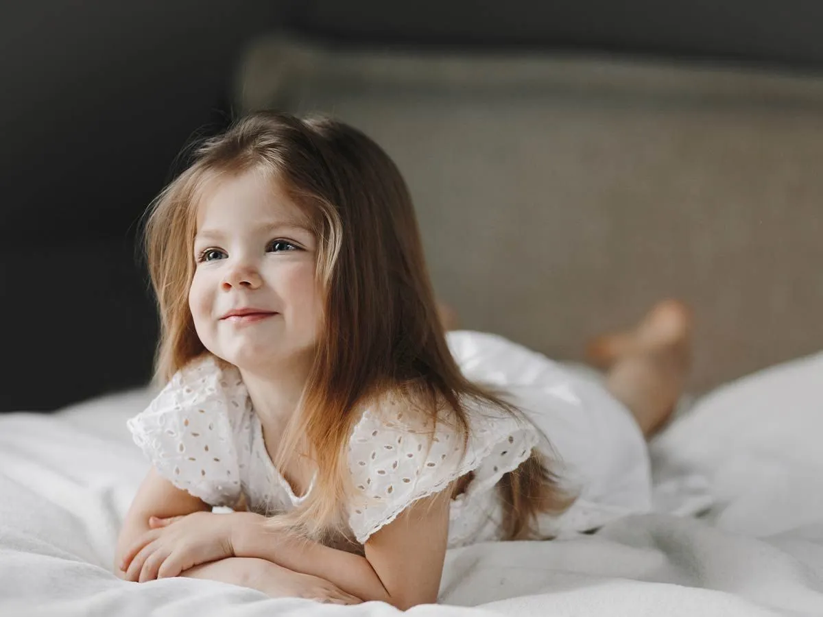 Little girl lying on the bed smiling as she listens to deer puns.
