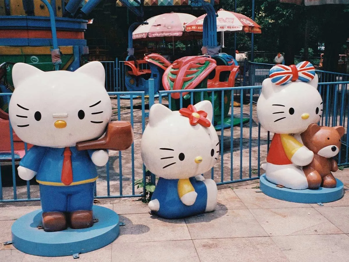 Three plastic Hello Kitty statues placed outside a children's playground.