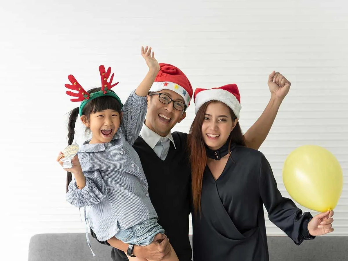 Happy family, the parents wearing Santa hats and the daughter wearing reindeer antlers.