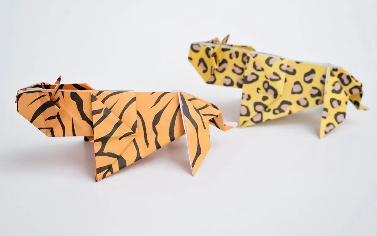 Two origami wild cats: one tiger made from orange paper with stripes, and one cheetah.
