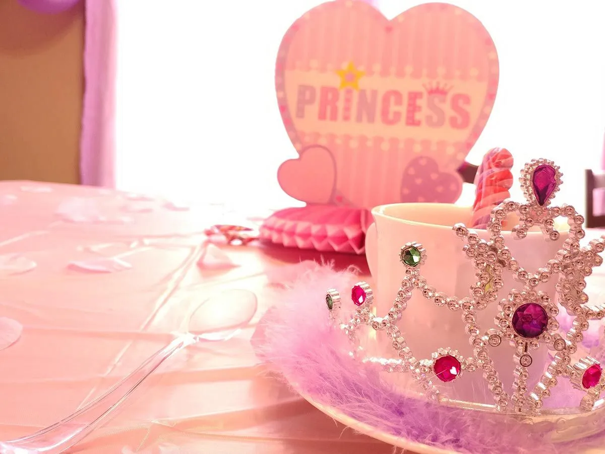 Princess party table setting, pink table cover, pink decorations and a tiara.
