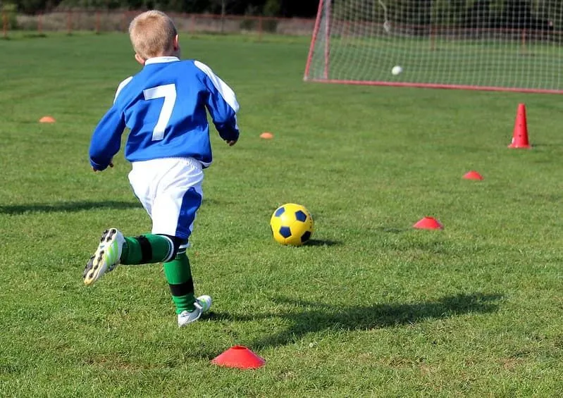 Young boy playing football wearing a blue jersey with number 7 on the back.