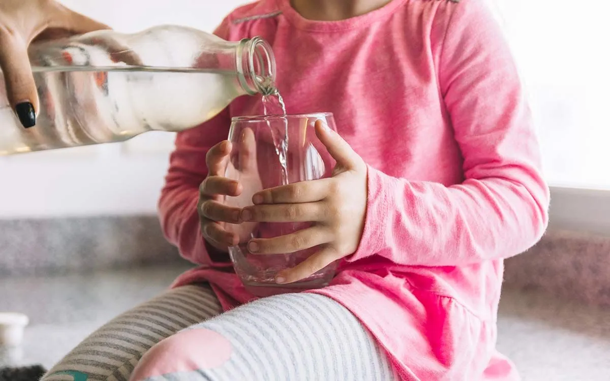 Mum pouring water in her daughter's glass - an example of a liquid for KS2 kids.