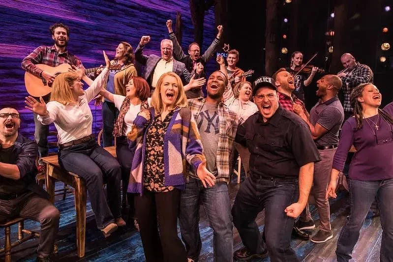 The cast of Come From Away in a group on stage singing a lively song.