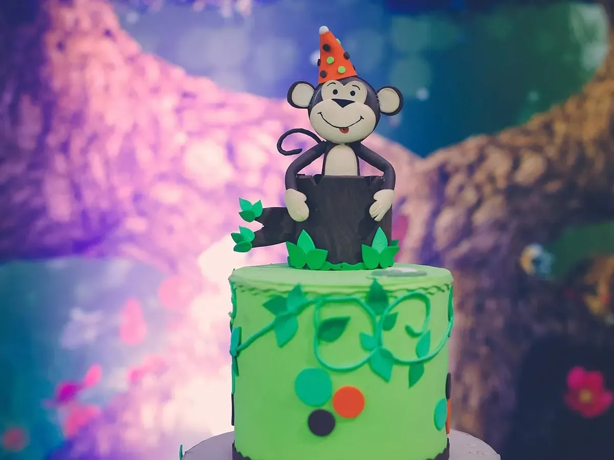 Green birthday cake with a monkey topper.