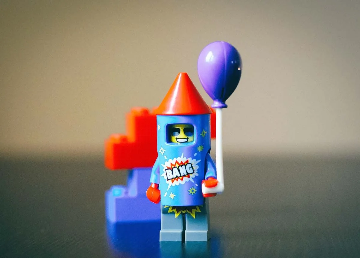 A little Lego firework rocket holding a Lego balloon.