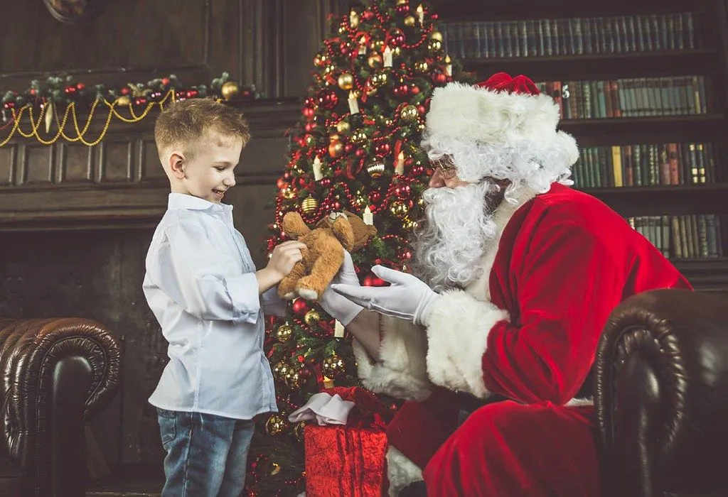A little boy meeting Father Christmas in a Christmas grotto.