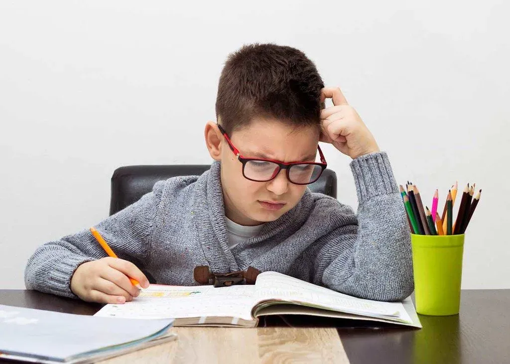 A boy is sat at his desk looking puzzled as he tried to work out some science riddles.