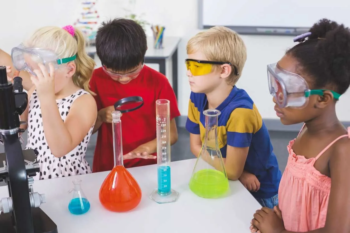 Four children wearing safety goggles doing a science experiment.