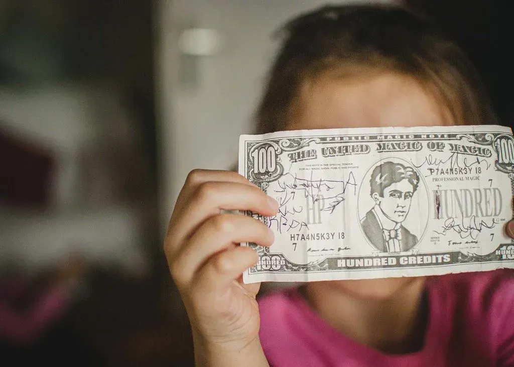 A close up image of a little girl holding some money up to the camera.