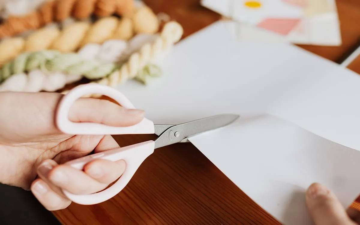 A child using scissors to cut a piece of origami paper.