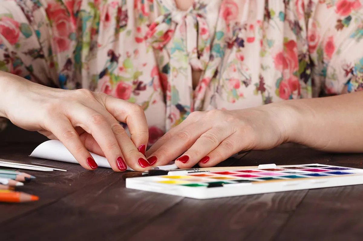 A close up image of someone folding a piece of paper to make an origami monkey.