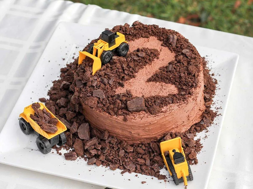 A chocolate birthday cake with toy tractors on top acting as tractor cake toppers.