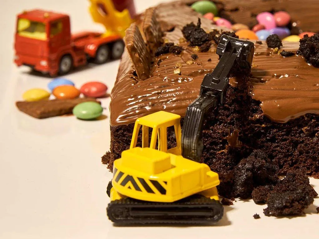 A close up image of a toy vehicle on a construction themed birthday cake.