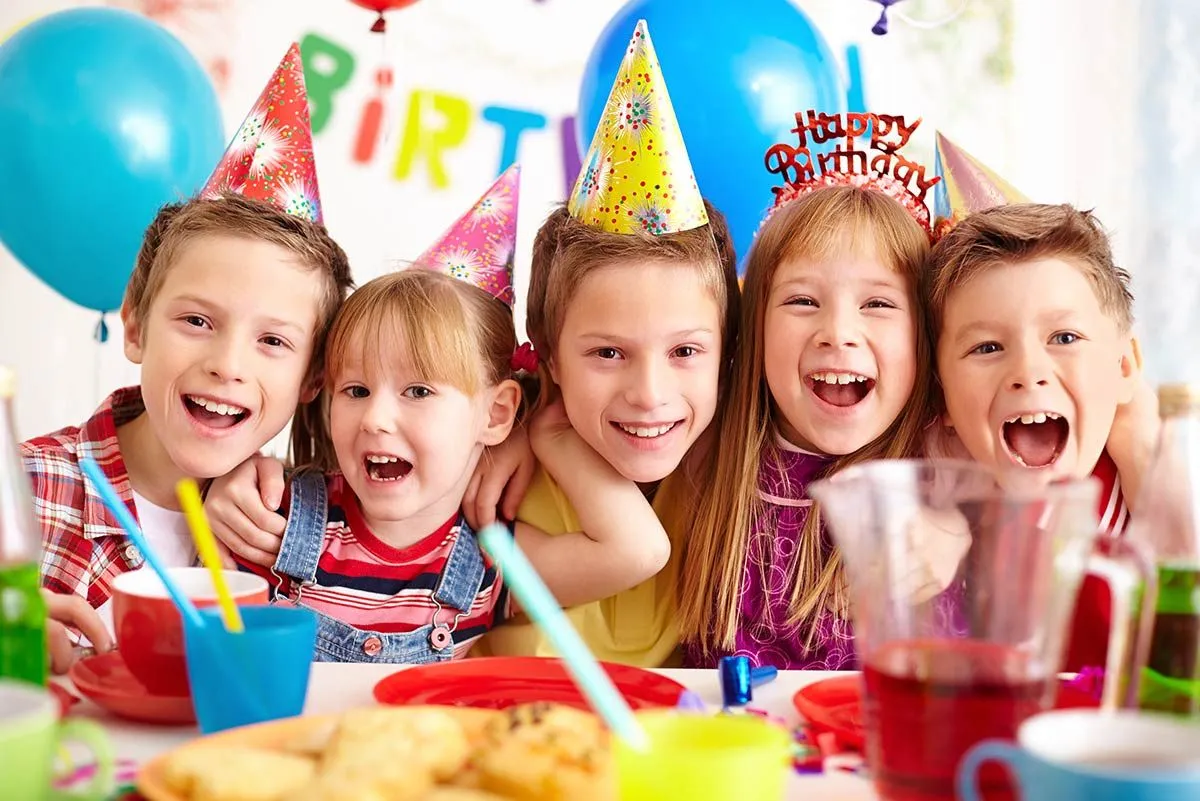 A group of kids smiling as they eat cake at a birthday party.