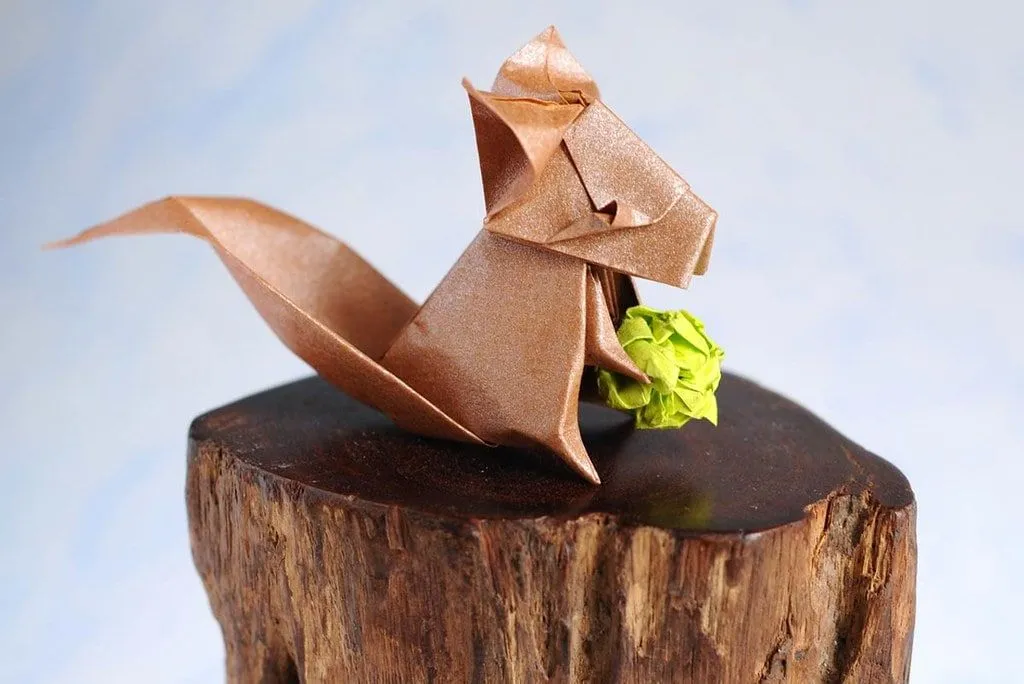 Origami squirrel holding an origami acorn.