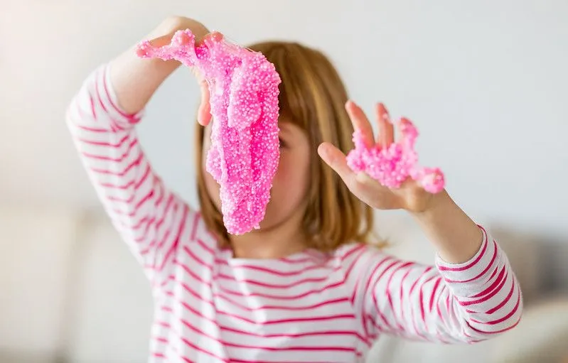Girl having fun playing with pink slime.