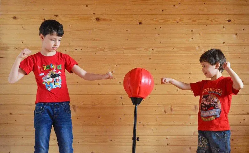 Kids hitting punching ball together inside