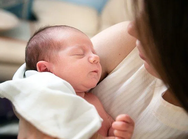 A newborn baby is sleeping in the arms of his mother