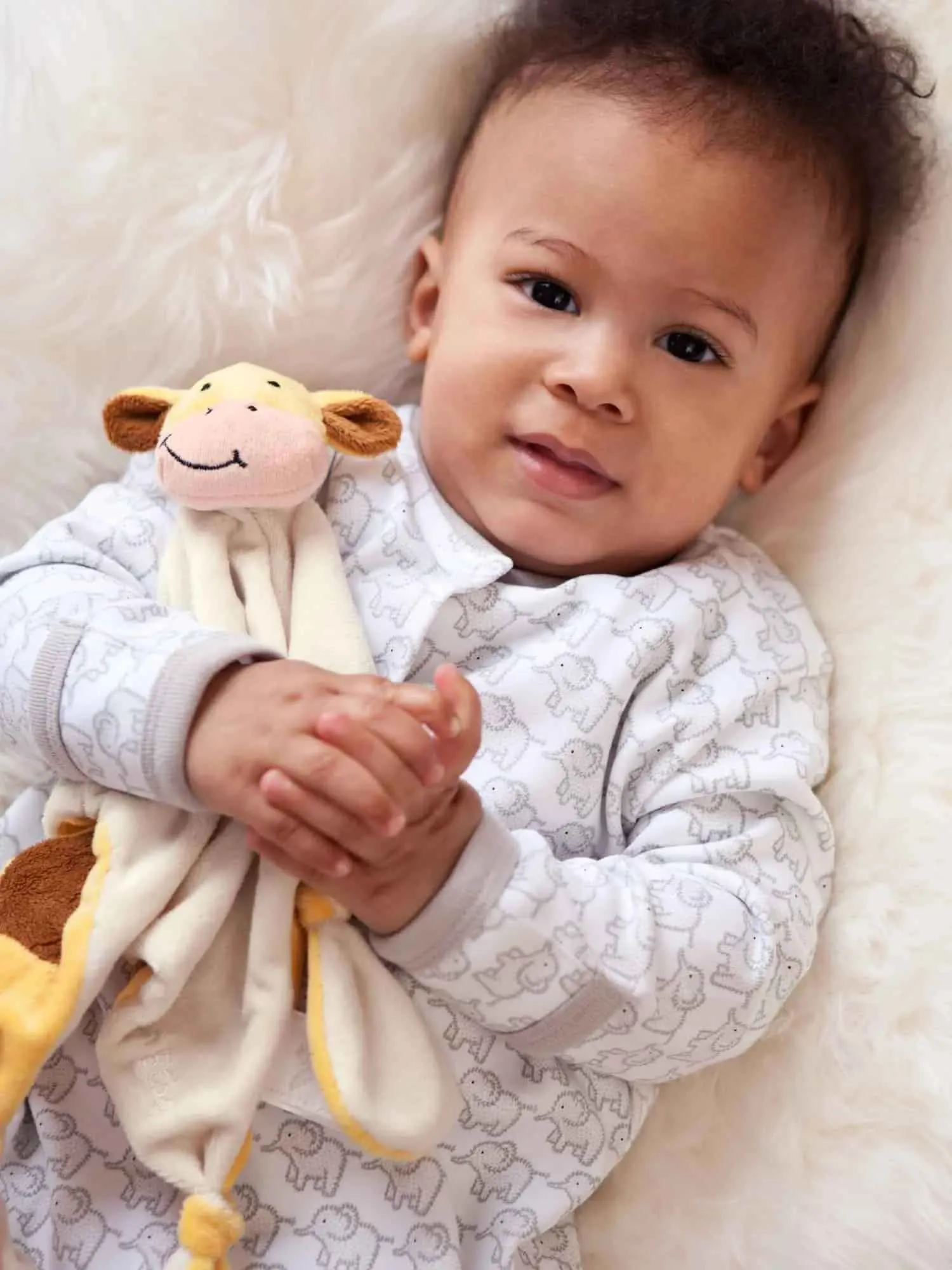 Baby holding extra soft and cuddly giraffe comforter.