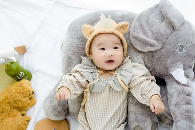Charming baby happily lying over a stuffed elephant toy.