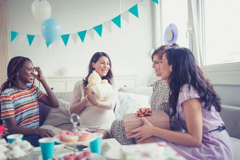 four friends at a baby shower smiling and talking