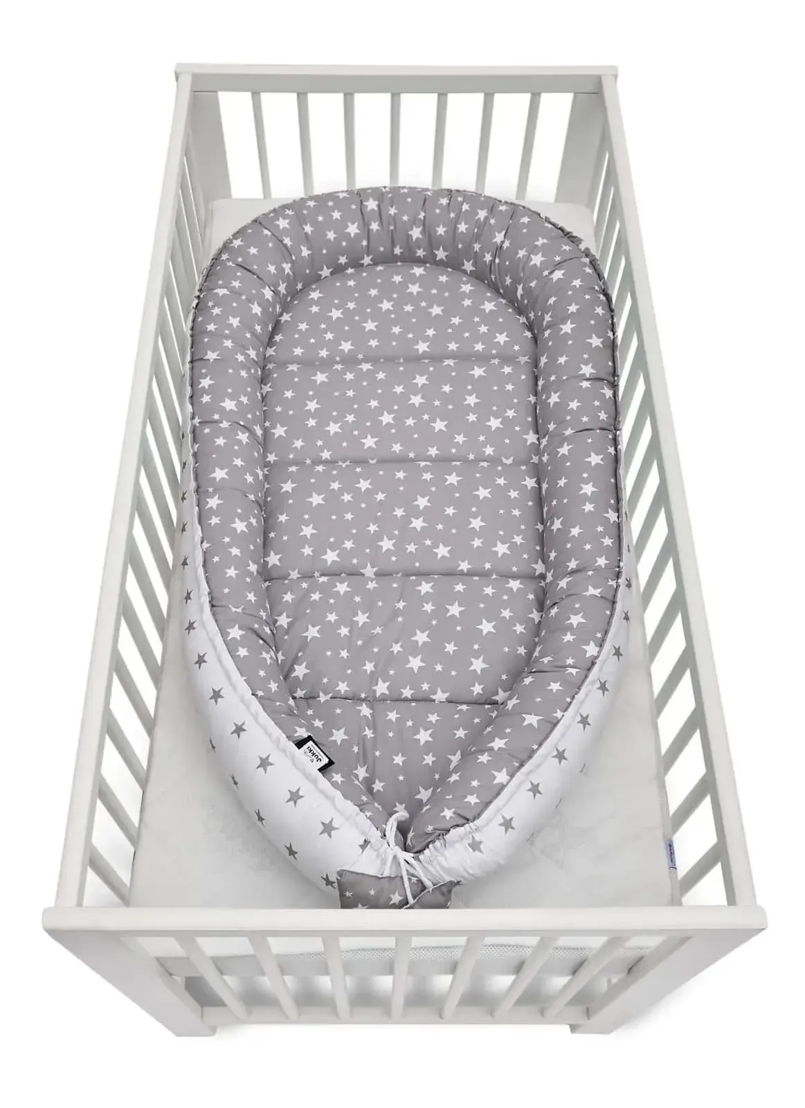 Elegant grey stars baby nest cocoon inside the crib.
