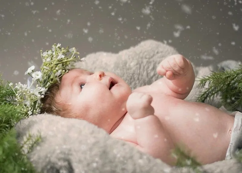 A happy newborn baby watching snow fall 