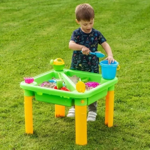 Little boy playing sand in the green splash and sand table.