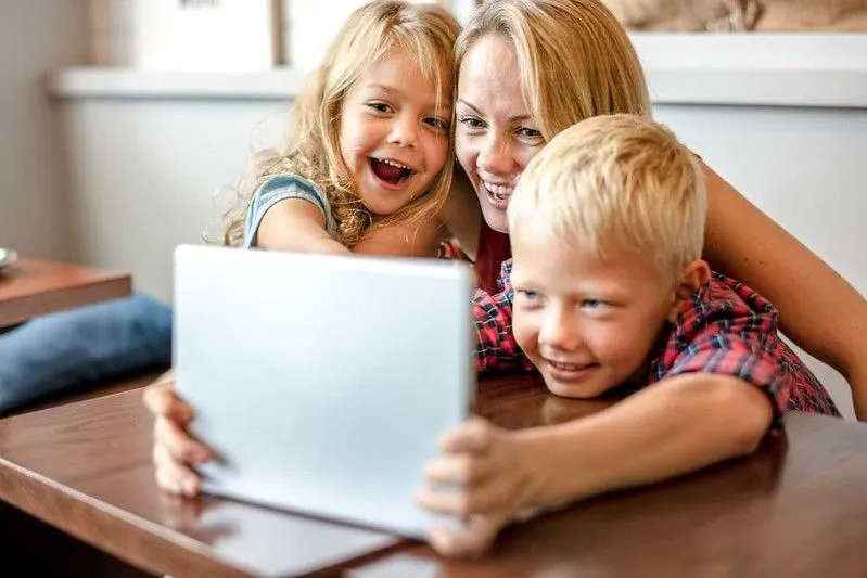 A mum and two children laughing at jokes on a laptop.