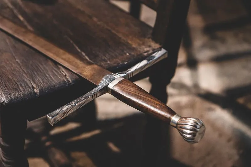 Close up of a sword with wooden handle on a wooden table