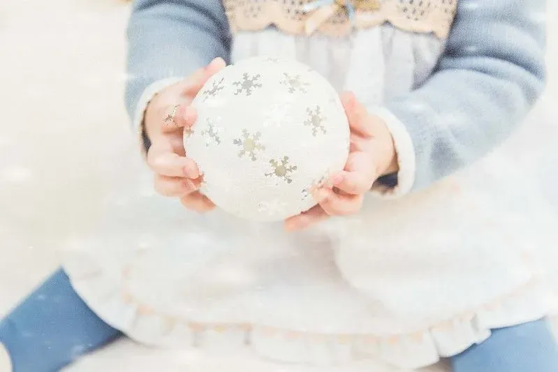 Child holding bauble Christmas gift that will be treasured forever.