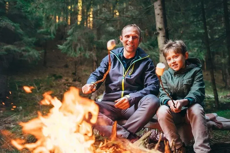 Dad and child by fire camping. 