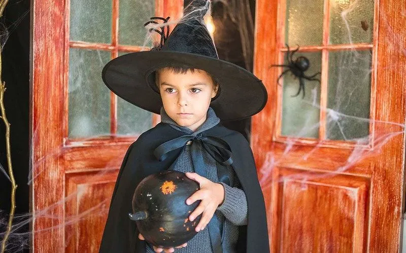 Boy in wizard outfit holding mystic ball. 