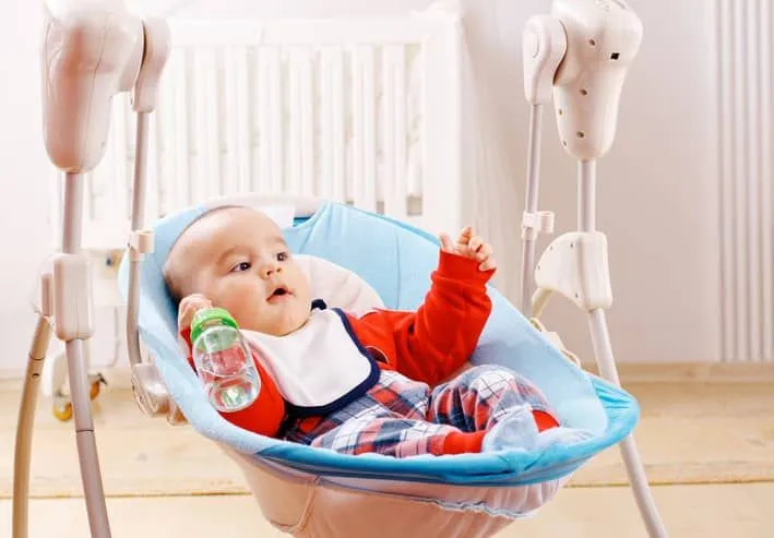 Boy in baby swing with bottle. 