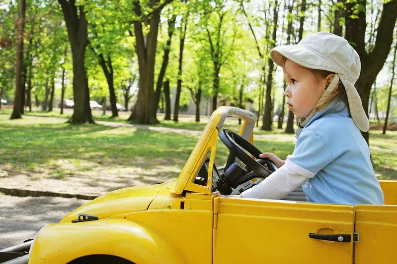Child in yellow car driving. 