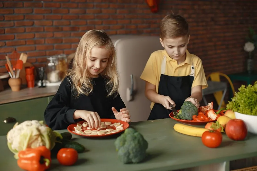 Young brother and sister preparing food in the kitchen.