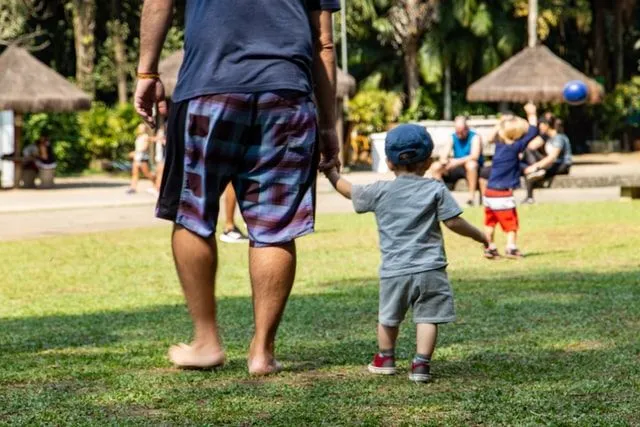 A father walking with his son by holding hands.