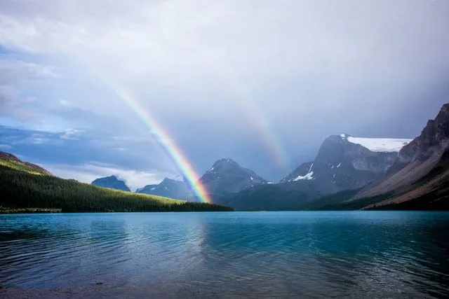Rainbows and mountains and a lake create beautiful colors combinations.