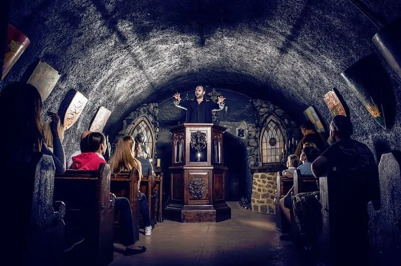 Visitors at the London Bridge Experience in a crypt watching one of the performers. 