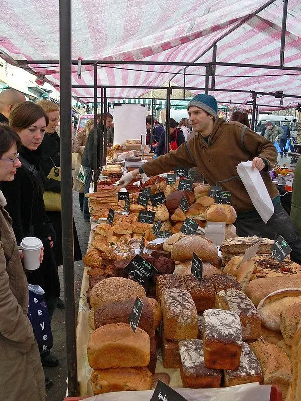 A man selling loaves of bread at a stall at Broadway Market.