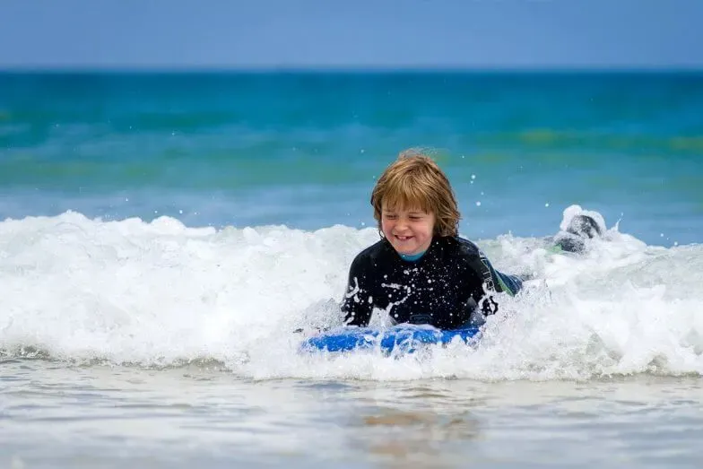A boy bodyboarding in the waves at Carbis Bay Beach.